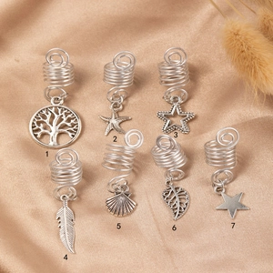 Macro shot of silver metal hair coils with diverse bohemian charms on silk fabric