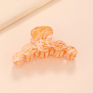 Détail de la pince à cheveux à texture marbrée orange et design géométrique