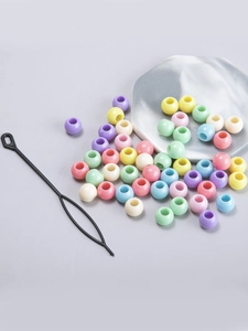 Close-up of colorful macrame hair beads in macaron tones with a black threading tool