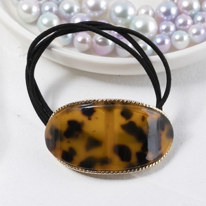Detail of tortoise shell acetate hair tie with golden metal rim and black elastic band