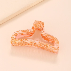 Vue détaillée de la pince à cheveux orange à motif marbré et design ajouré