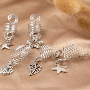 Silver alloy hair rings with starfish, leaf, and shell charms on champagne satin background