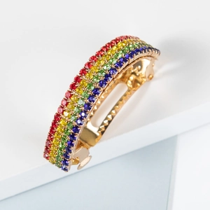 Barrette à cheveux avec cristaux arc-en-ciel et base dorée sur un support minimaliste