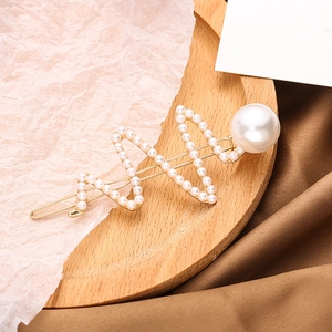 Barrette à cheveux dorée en forme de vague avec perles sur une assiette en bois vintage