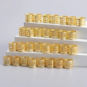 Golden hollow floral pattern hair rings for dreadlocks displayed on a white tiered stand