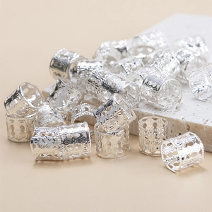 Close-up of silver metal dreadlock cuffs with intricate hollow flower patterns