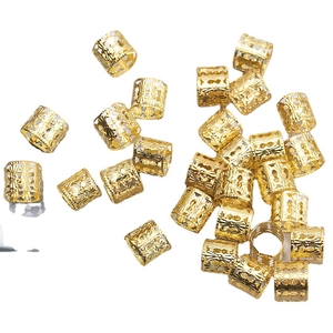 Golden hollow dreadlock metal rings with intricate carved patterns on white background