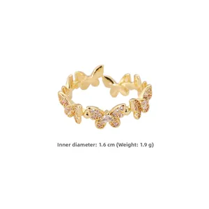 Dettaglio di anello a farfalla dorato con zirconi rosa e design aperto regolabile