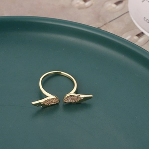 Elegante anello aperto dorato a forma di ali con zirconi su vassoio verde scuro
