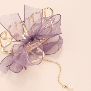 Détail de la pince à cheveux en métal doré avec nœud en maille mauve et perle