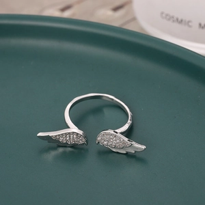 Elegante anello aperto argento con ali di piume in cristallo su vassoio verde
