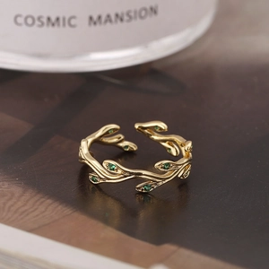 Detailaufnahme des goldenen Ringes in Zweigform mit grünen Steinen und Öffnung