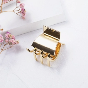 Elegant gold metal hair claw clip for high ponytail styling on a decorative background