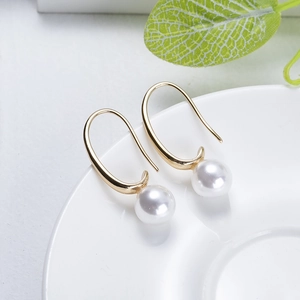 Élégantes boucles d'oreilles perles avec crochets dorés sur une assiette blanche en céramique