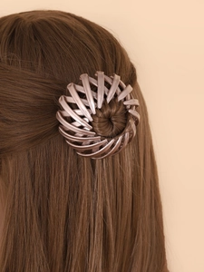 Rose gold bird nest hair clip securing a bun on light brown hair in a clean lifestyle shot
