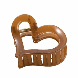 Détail d'une pince à cheveux marron en forme de cœur avec ressort doré et finition en résine