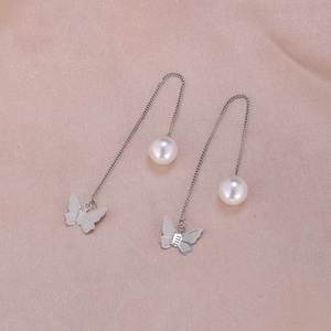Detail view of long silver chain earrings with white pearls and hollow butterfly charms