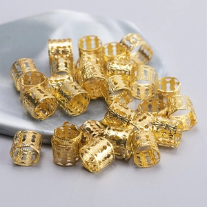 Golden spiral hollow metal hair rings for braids on a marble tray in vintage style