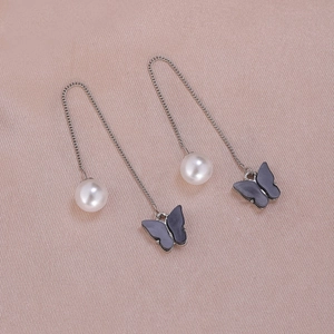 Detailed macro view of elegant pearl tassel earrings featuring butterfly and chain design
