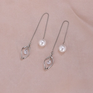Detail of silver tassel earrings with white pearls and leaf-shaped rhinestone charms