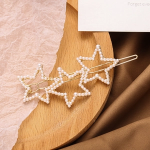 Elegant gold hollow star hair clip with pearls on a wooden tray with silk fabric