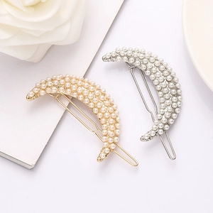 Elegant gold and silver crescent moon hair clips with white pearls in a minimalist flat lay