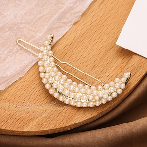 Elegant gold crescent moon hair clip with white pearls for women on vintage warm background