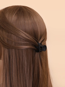 Mini pince à cheveux noire mate pour enfant montrée sur une coiffure demi-attachée