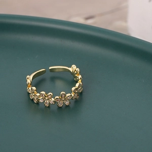 Dettaglio macro di un anello dorato regolabile con motivi a fiori e pietre di zircone bianco