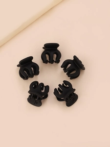 Gros plan de cinq mini-pinces à cheveux en plastique noir mat sur un fond beige