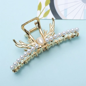 Détail de la pince à cheveux dorée en forme de bois avec perles et strass