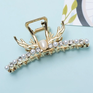 Détail d'une pince à cheveux dorée en forme de bois avec perles et strass brillants