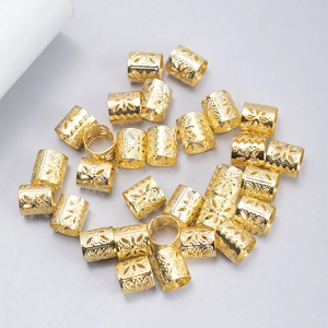 Detailed view of hollow carved gold metal dreadlock hair rings and cuffs for braiding