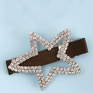 Détail d'une pince à cheveux étoile en strass avec ruban marron et clip bec de canard