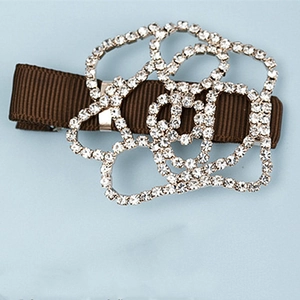 Détail de la pince à cheveux camélia en strass sur base de ruban gros-grain marron