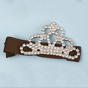 Détail d'une pince à cheveux en forme de couronne avec strass brillants et ruban marron
