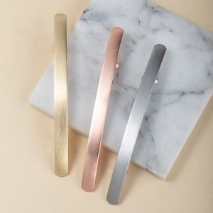 Trois barrettes minimalistes en métal brossé aux finitions dorées, rosées et argentées