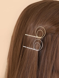 Détail de barrettes circulaires minimalistes dorées et argentées sur cheveux