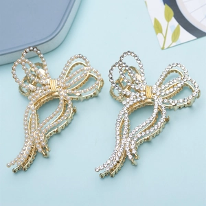 Elegant gold bow hair claw clips with pearls and rhinestones on light blue background