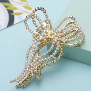 Elegant gold bow hair claw with pearls and tassels on a refreshing blue backdrop