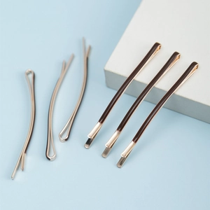 Set of six brown enamel bobby pins with gold-tone metal finish on white stone
