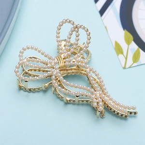 Close-up of golden metal butterfly hair claw clip with elegant faux pearl embellishments