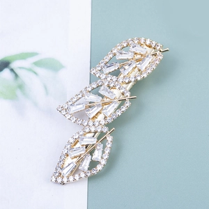 Détail de la pince à cheveux trèfle doré avec strass cristal et motif en métal creux