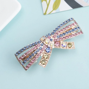 Bow-shaped hair clip with colorful rhinestones on a metal base in a stylish top view