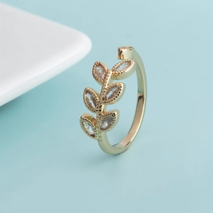 Close-up of golden leaf open ring with marquise-cut zircons on a light blue background