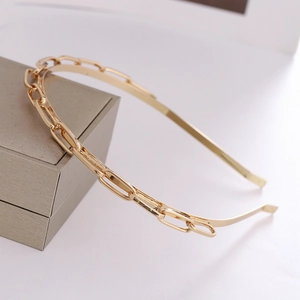 Serre-tête minimaliste en métal doré avec design de chaîne sur fond gris clair
