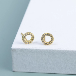 Golden circular stud earrings with pavé set micro zircons on a white display stand