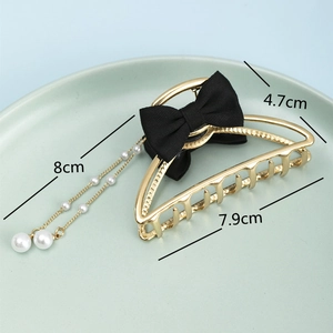 Detail of gold metal hair claw with black mesh bow and long faux pearl tassel charms