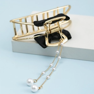 Detail of golden metal shark hair clip featuring black mesh bow and pearl tassel chain