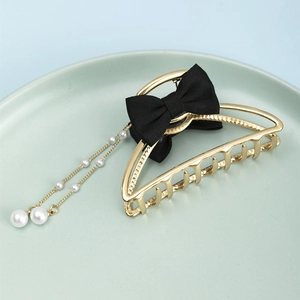 Detail of gold metal hair claw with black mesh bow and dangling white pearl tassels